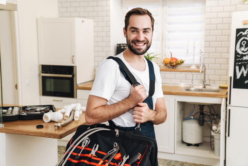 crm for home service companies  - image-of-plumber-man-smiling-and-holding-bag